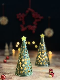 Ażurowa choinka ceramiczna 17 cm stojąca na drewnianym blacie z drobnymi bombkami w tle