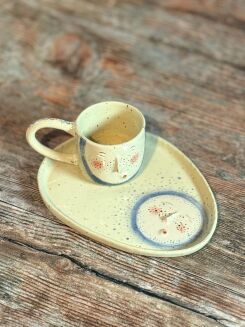 Rękodzieło z nakrapianej gliny – filiżanka z twarzą i talerzyk o organicznym kształcie.